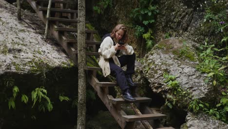 woman sitting on wooden stairs in a forest