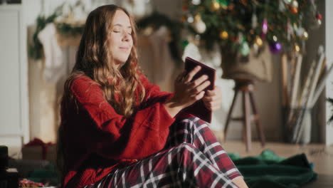 vrouw die een boek leest en met gesloten ogen zit in een helder huis tijdens kerstmis