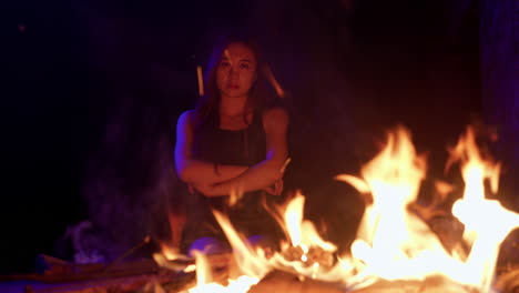 mirando seriamente a la cámara mujer asiática frente a la hoguera fuego llama brazos cruzados