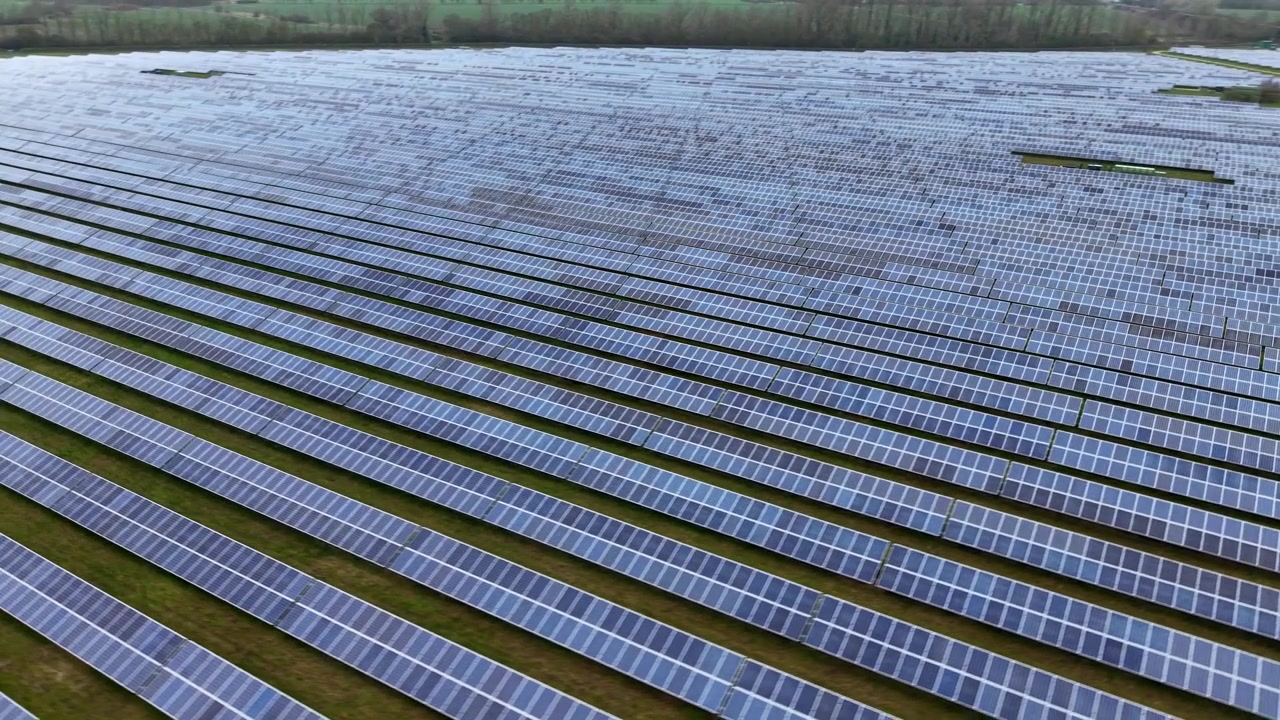 Skråt luftfoto fra høj vinkel af et storskala solcelleanlæg, der genererer ren energi på det britiske landskab