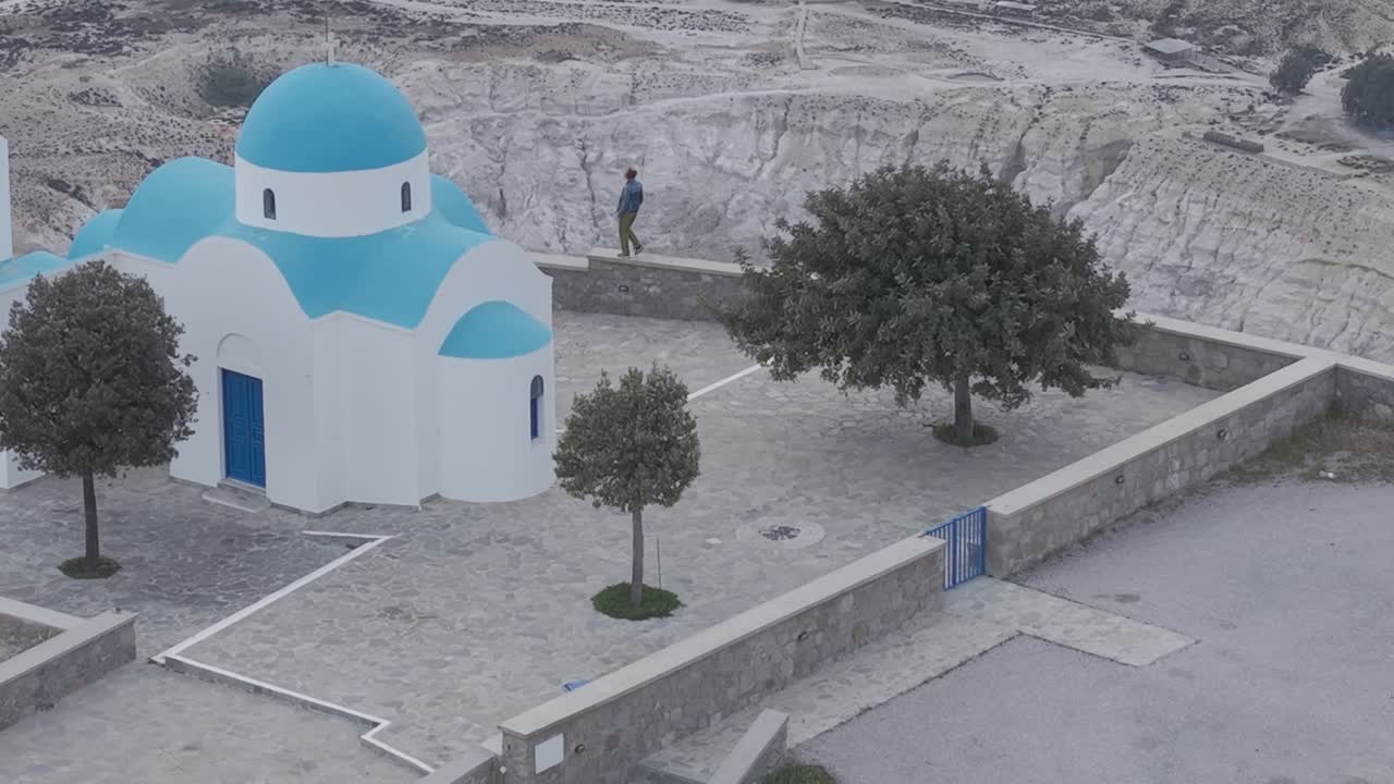 Stunning aerial of woman standing on profitis ilias church revealing volcanic caldera behind it.
Blue Dome Church of Nikia village, island Nisyros Greece stock video. 3x telephoto. D-Log M profile