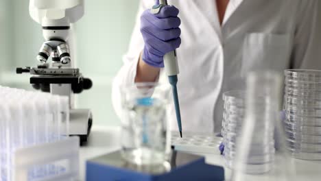 a scientist performing a laboratory experiment with a pipette and microscope
