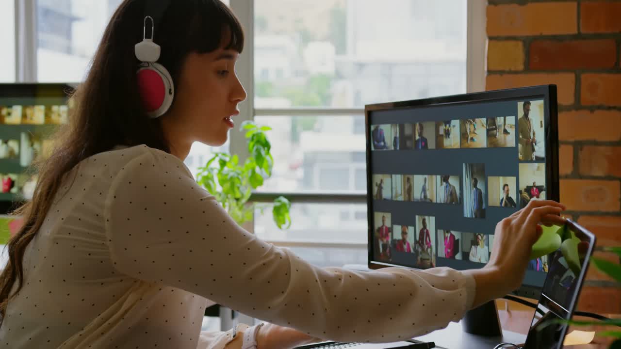 Naispuolinen graafinen suunnittelija kuuntelee musiikkia työskennellessään pöydän ääressä 4K.