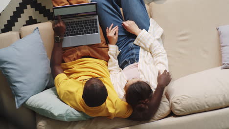 casal navegando na web no laptop e conversando no sofá