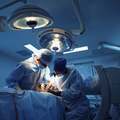 group of doctors in the operating room. medical specialists in blue masks and uniform are performing an operation in clinic. medical surgery