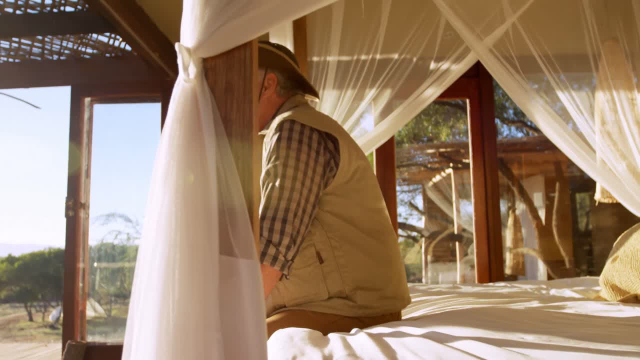 hombre con maleta tendida en la cama en el resort 4k