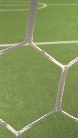 slide shot behind empty football goal keepers net on 5-a-side pitch vertical