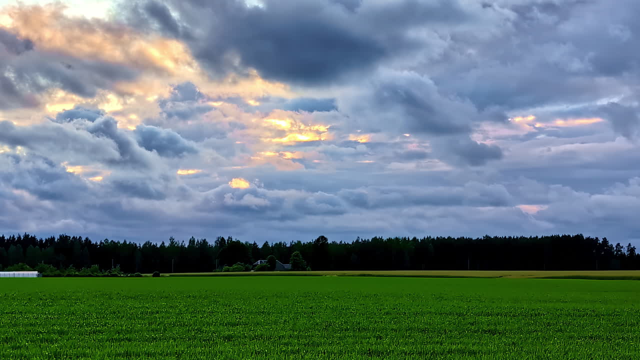 Vast Green Field Beneath Dramatic Cloudy Sky with Sunlight Breaking Through
