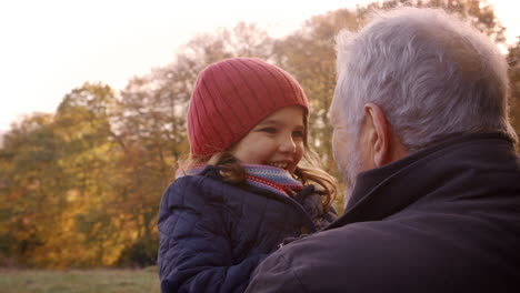 Grandfather-Walking-With-Granddaughter-In-Autumn-Countryside