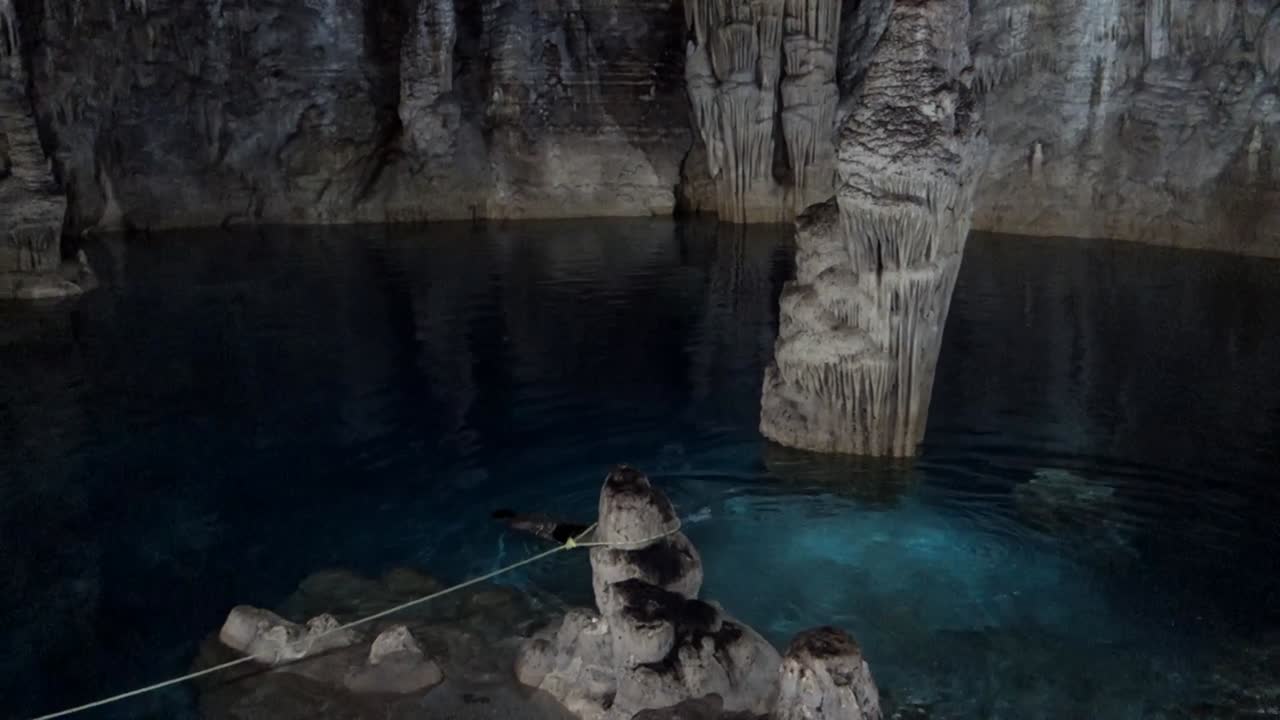 el hombre nada en las aguas cristalinas del cenote subterráneo.