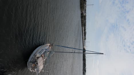 aerial shot flying past sailboat on peaceful water - vertical video