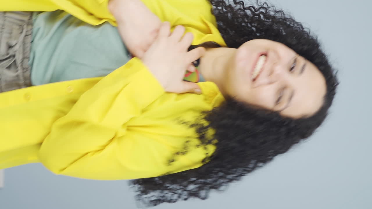 video vertical de la joven que felizmente pone el teléfono a su corazón.