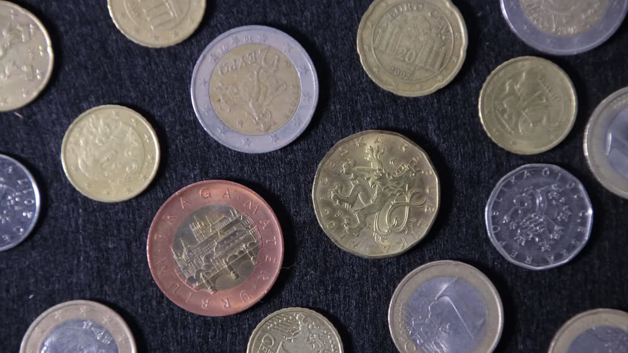 patrón de monedas de diferentes países europeos en una tela de textura negra, vista desde arriba, primer plano.