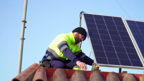 close shot of technician guy with uniform installing solar panels over bricked roof