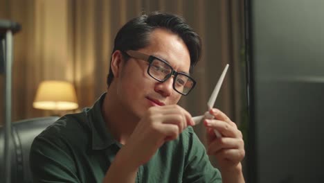 asian man looking at wind turbine model from 3d printer and works on personal computer, he works at night