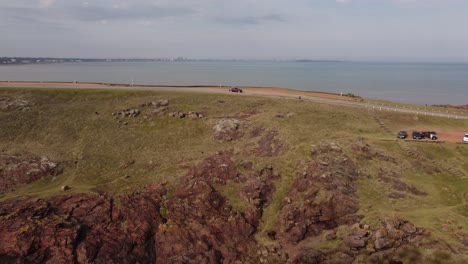 Aerial-tracking-shot-of-car-arriving-Viewpoint-on-Hill-in-Punta-Ballena-with-ocean-in-background-during-sunny-day