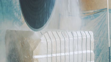 a large circular saw with water cuts the sandstone into individual slabs. factory of products from a natural stone