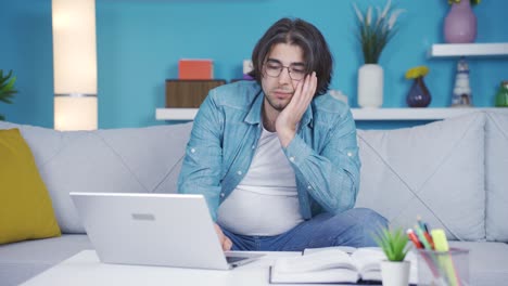 bored and troubled young man looking at laptop.