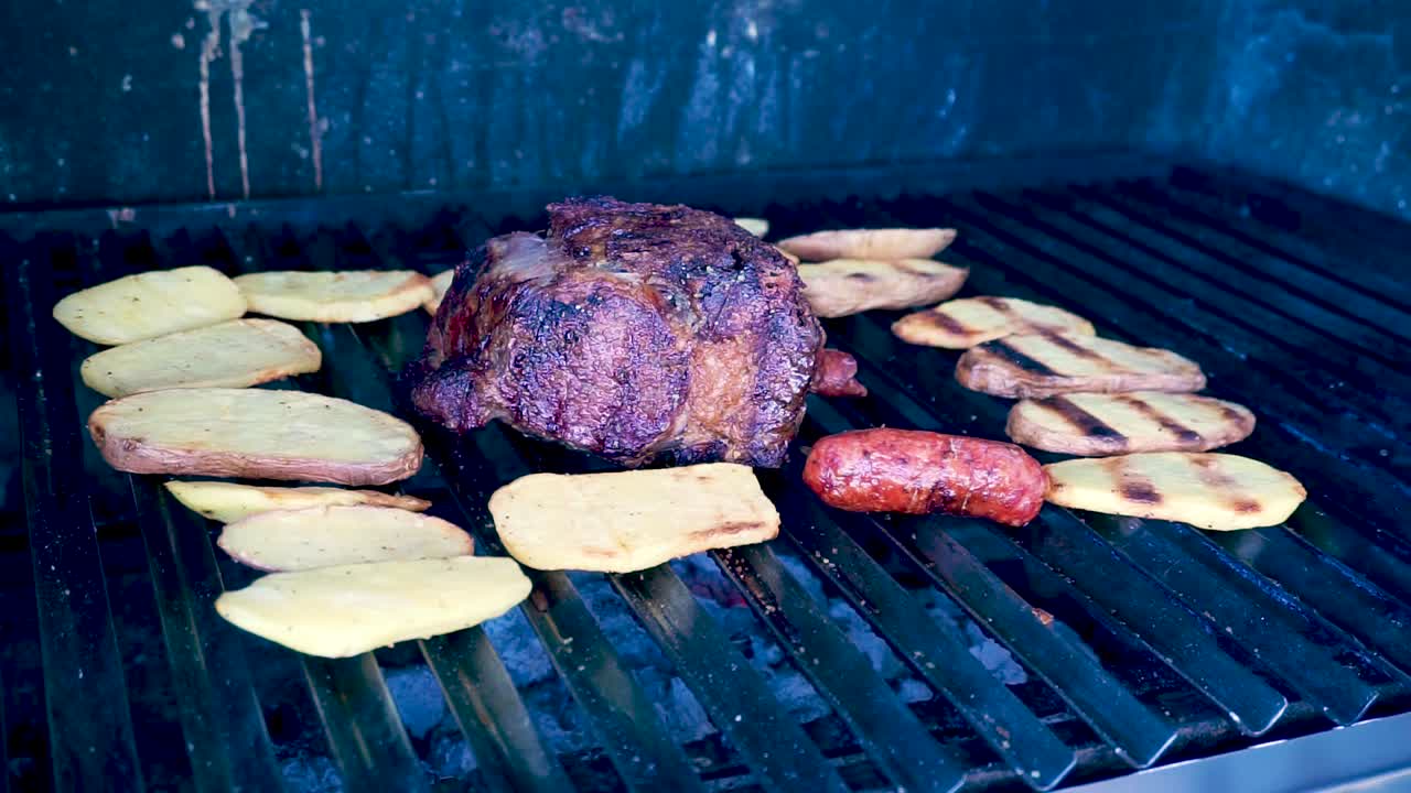 en primer plano, carne a la parrilla con chorizos, tortillas de queso, frijoles guatemaltecos y patatas asadas fumando y preparación jugosa lista para comer en familia en un día de la temporada de verano [hd1920 x 1080] fps 29