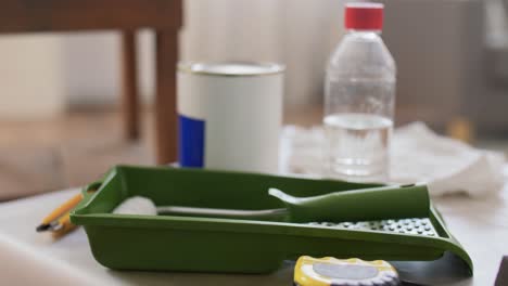 Paint-Roller-and-Bottle-of-Solvent-on-Table.repair,-building-and-home-improvement-concept--paint-roller-and-bottle-of-solvent-on-table