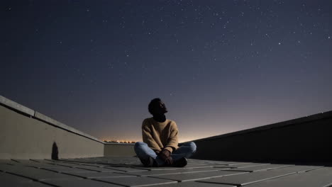 man contemplating the night sky on a rooftop