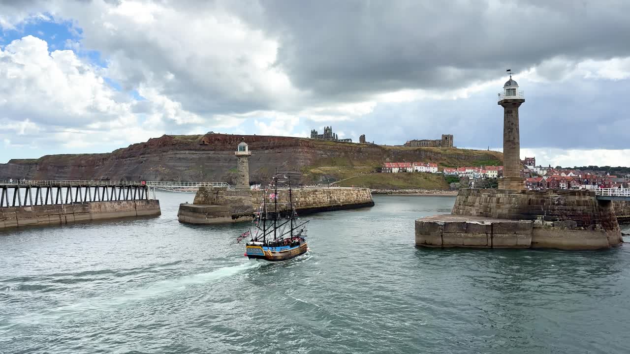 Tall ship entering harbour with Whitby Abbey on hilltop in distance. Whitby - North Yorkshire, UK