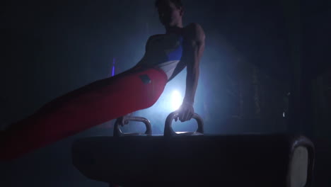 male-gymnast-athlete-performs-handstand-and-spin-on-Pommel-horse-on-a-dark-background-and-smoke-in-slow-motion.-Olympic-programme.-Preparation-for-the-exercise