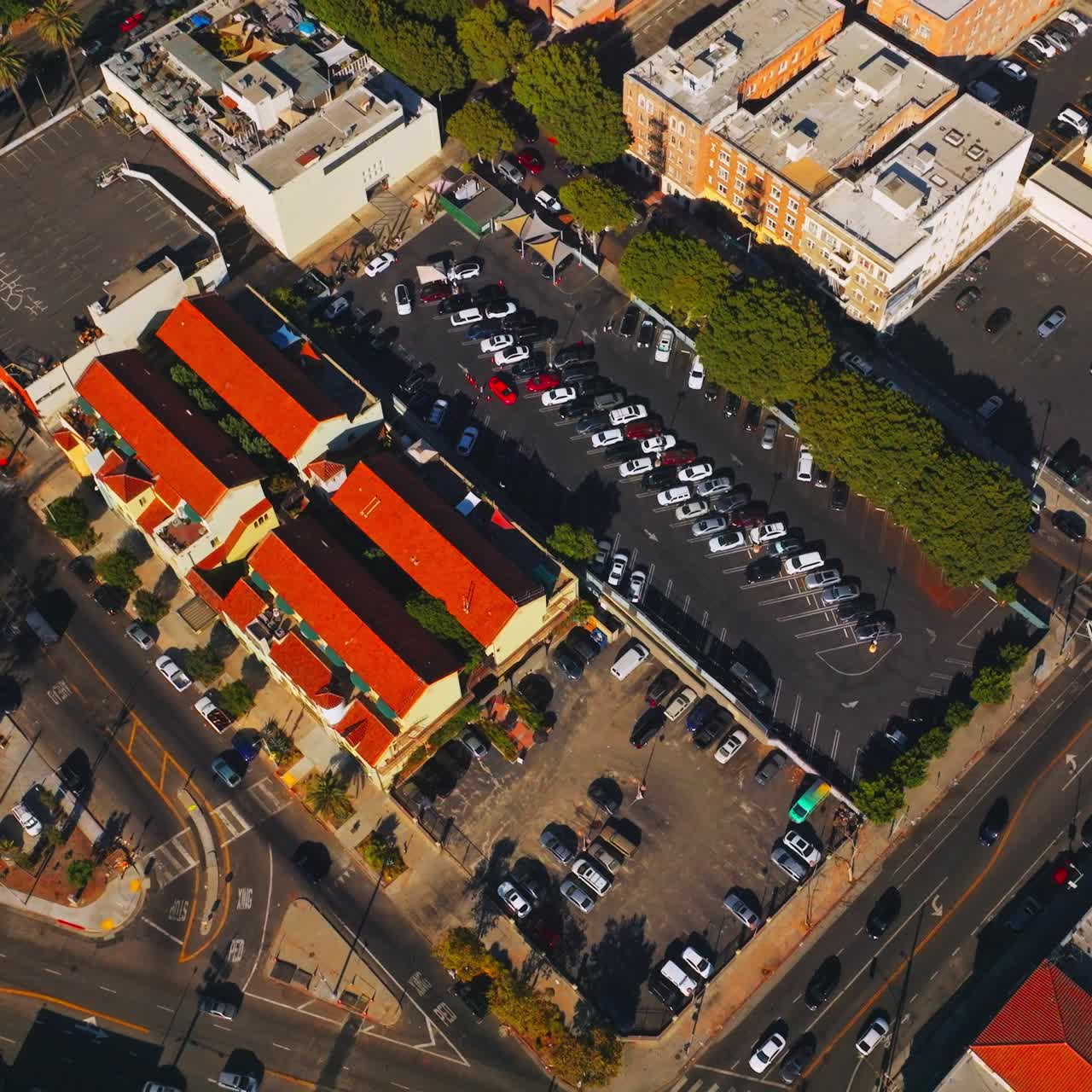 Streets of Los Angeles, United States with private transport moving around. Parking lots busy with cars. Top view