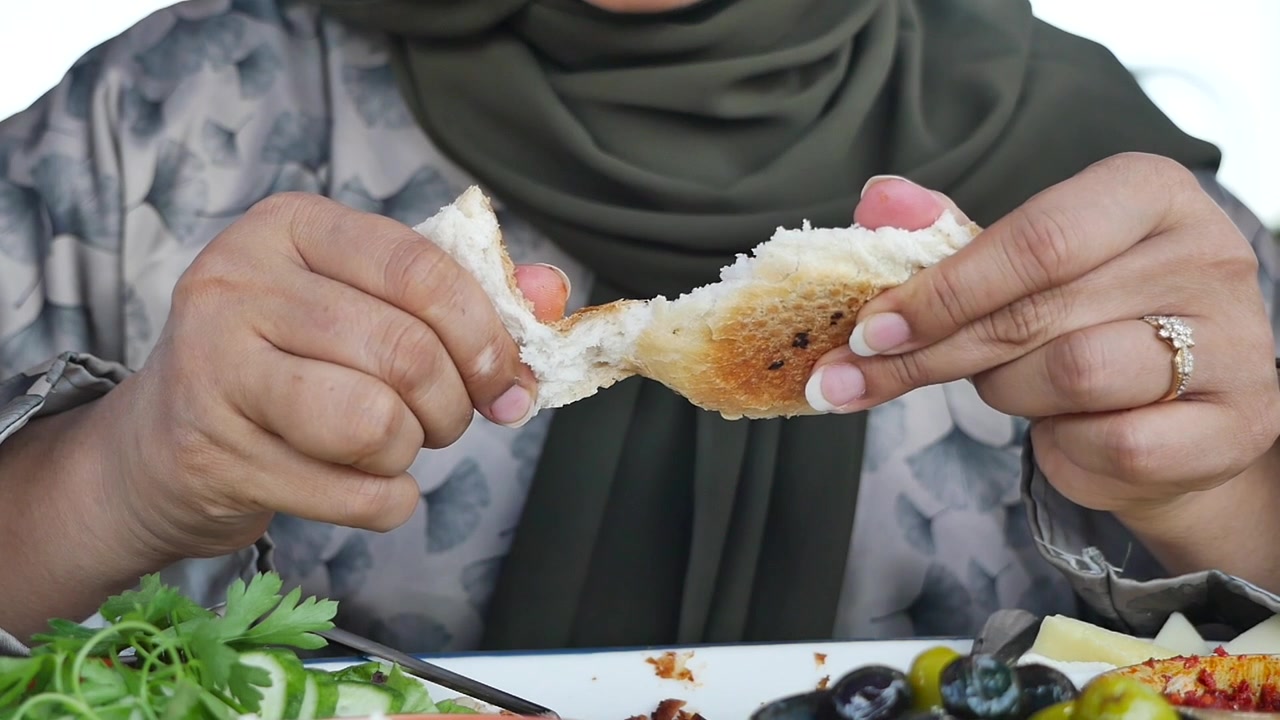 Woman in Hijab Tearing Fresh Bread at a Meal