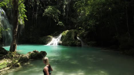 female tourist walks on slippery rock at cambais waterfall in thick jungle