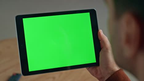 usuario sosteniendo una computadora chromakey en un lugar cerrado. hombre leyendo un dispositivo de plantilla