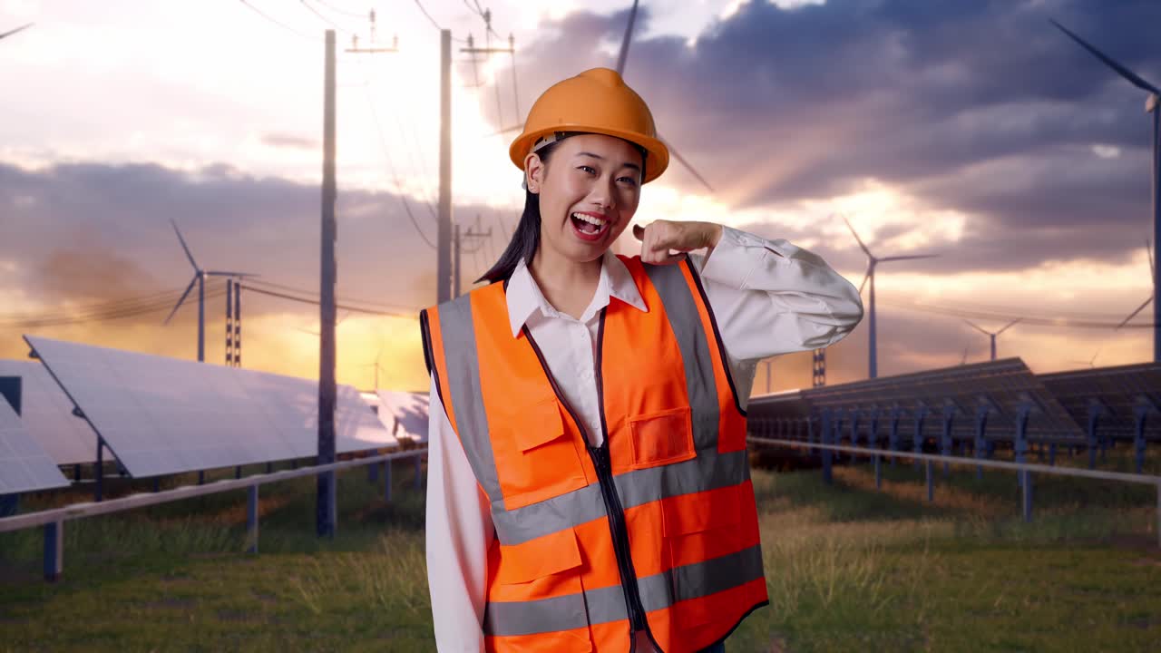 Asian Female Engineer With Safety Helmet Smiling To Camera And Making Call Me Gesture With Solar Panel and Wind Turbines