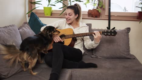 young woman playing guitar while her dog is singing