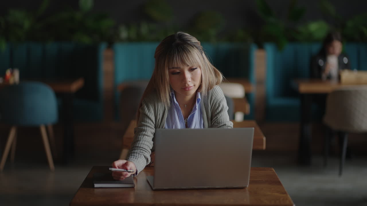 An Asian woman sits brooding and looks at a laptop screen. Brainstorm ...