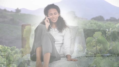 animation of smiling woman relaxing talking on smartphone, over landscape
