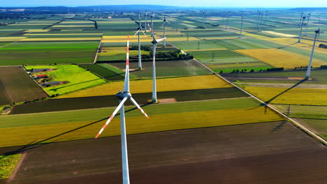 vast agricultural field divided into multiple colorful patches. numerous wind turbines are installed in the countryside. aerial view