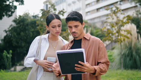 Focused-colleagues-reading-papers-outdoors.-Business-partners-working-walking