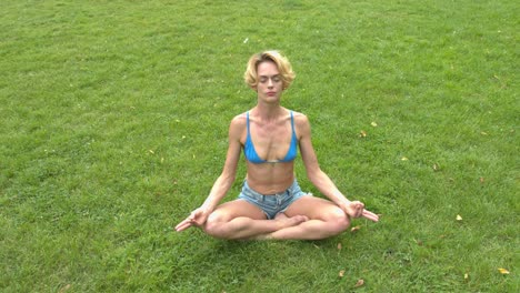 a woman sitting on the soft green grass meditating