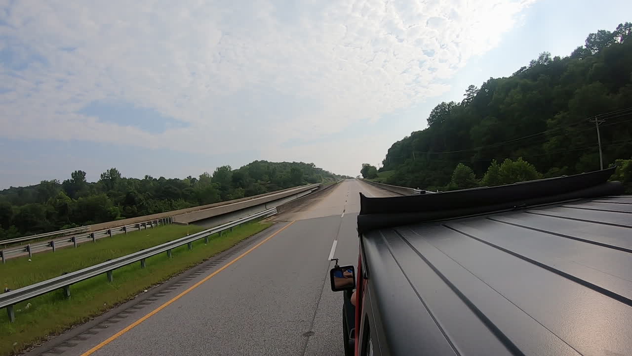 Rooftop view of driving on a divided highway past heavily timbered landscape in rural Alabama