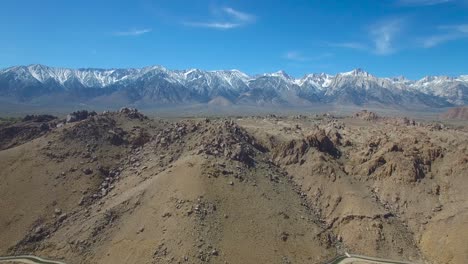 a rising aerial over the alabama hills of california reveals the towering and snow covered sierra nevada mountains 1