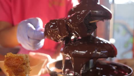 Chocolate-fountain-drizzling-melted-chocolate-on-brownies-on-a-skewer-at-candy-stall