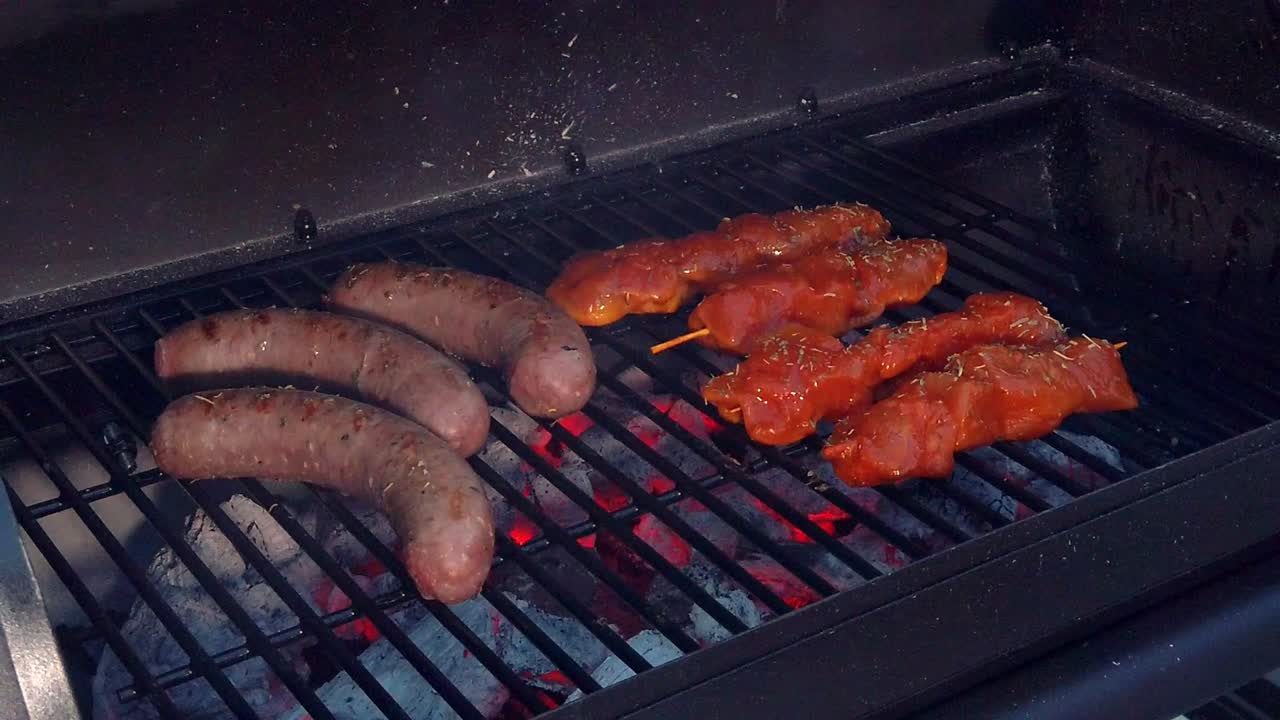 mirando las salchichas y el pollo sate recibiendo el calor y el humo de la barbacoa
