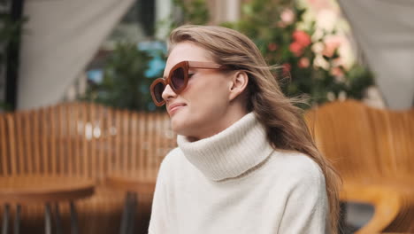 caucasian woman smiling in cozy sweater outdoors.