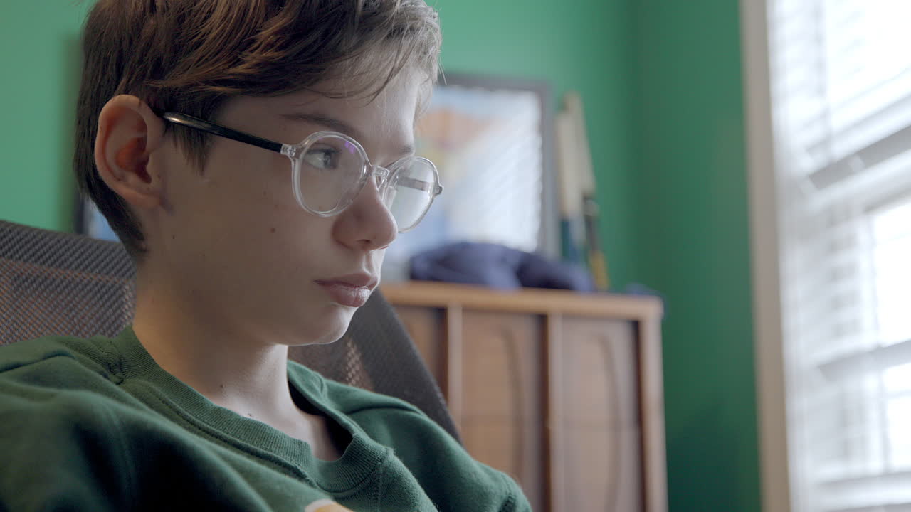 Portrait of an attractive young boy wearing glasses studying in his bedroom