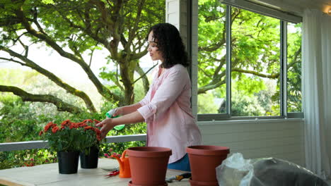 woman gardening on porch with potted plants and spray bottle, enjoying nature