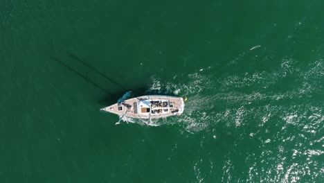 Aerial-establishing-view-of-a-white-sailboat-in-the-calm-Batltic-sea,-white-sailing-yacht-in-the-middle-of-the-boundless-sea,-sunny-summer-day,-birdseye-done-dolly-shot-moving-left