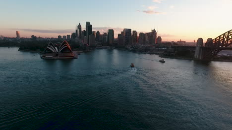 drone view of iconic sydney harbor at sunset, ferries crossing slow motion