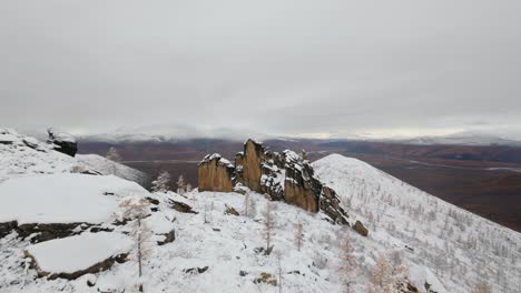 una impresionante vista aérea revela montañas cubiertas de nieve y afloramientos rocosos, destacando la belleza del toque del invierno en la naturaleza