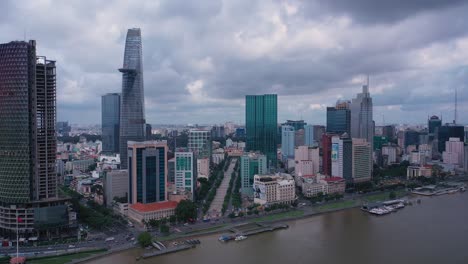 Toma-Aérea-Del-Horizonte-De-La-Ciudad-Durante-El-Día-Con-Un-Dron-Del-Centro-De-La-Ciudad-De-Ho-Chi-Minh,-Con-Todos-Los-Edificios-Clave-Y-Barcos-En-El-Río-Saigón