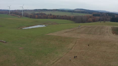 people planting new trees with wind power stations in background